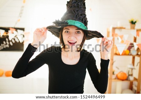 Young beautiful woman in witch costume ready for Halloween celebration in Halloween room decoration.