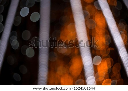 Fabulous bokeh of circles of fiery orange, crossed by bands of white lights from top to bottom.