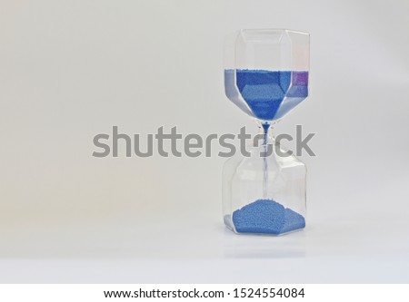 Old time measurement instrument with blue running sand. (hourglass, clepsydra)