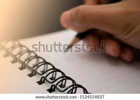 hands with pencil writing on notebook