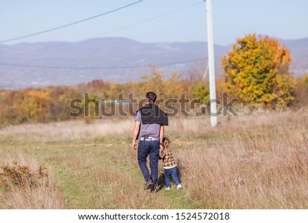 Man with daughter walking in autumn forest. Nature backgrounds photo