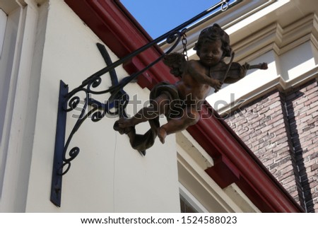 part of the facade of the workshop of a violin maker, with a wrought iron facade sign of a putto playing the violin. Zutphen, The Netherlands