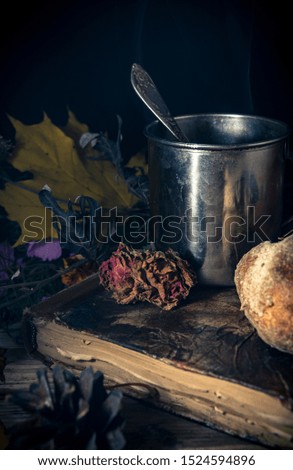 Steel cup of tea and a bun on a seasonal rustic background, close up still life