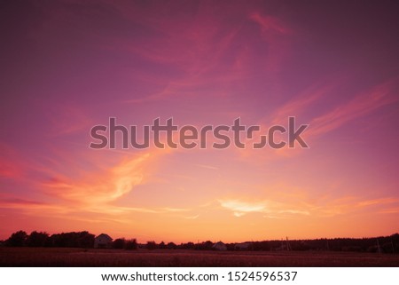 Rural landscape in evening in sunset light.  Silhouette of village on the horizon.