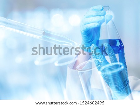 hand of scientist holding flask with lab glassware and test tubes in chemical laboratory background, science laboratory research and development concept