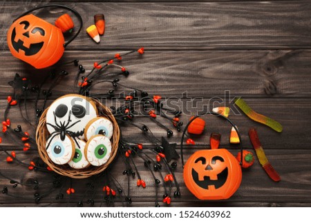 Halloween candies with gingerbread cookies and pumpkin buckets on wooden table
