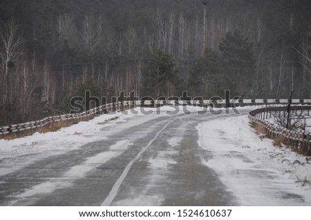 Empty snow covered road in winter landscape. Winter driving and danger of skidding. Space for text.