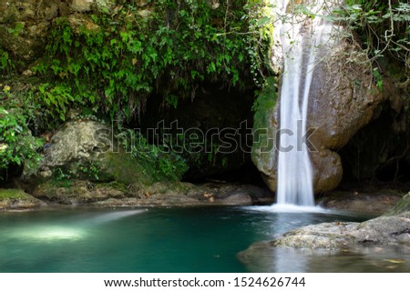 silky falling waters of a waterfall among green nature and rocks