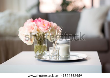 decoration, hygge and cosiness concept - aroma reed diffuser, candle and flower bunch on wooden table Royalty-Free Stock Photo #1524662459