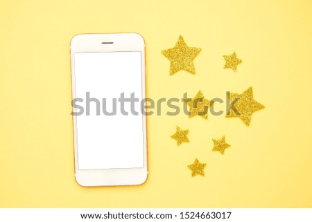 Mobile phone and brilliant glitter stars on a yellow background, technology and rating