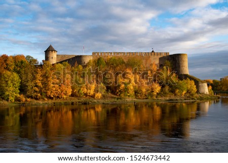 A medieval fortress by the water. Golden autumn is a favorite time for lovers of fishing and just walking.Ivangorod. Russia. Royalty-Free Stock Photo #1524673442