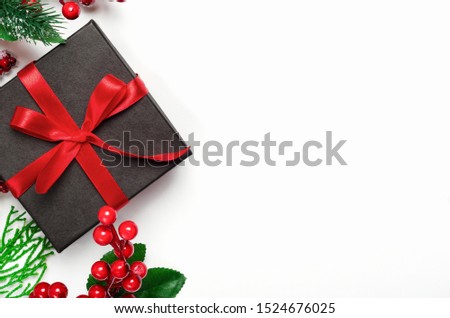 Gift box and holly ilex berries top view background. New year, Xmas present. Festive backdrop with copyspace. Christmas composition with decorative elements. Winter holidays concept