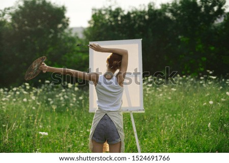 young woman with a white canvas on the nature easel