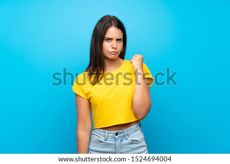 Young girl over isolated blue background with angry gesture