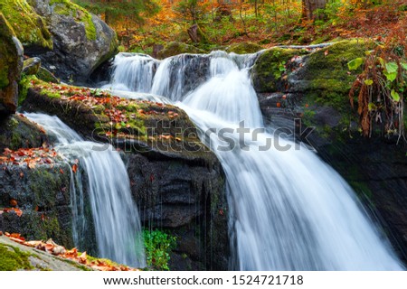 Beautiful mountain waterfall with trees, rocks and stones in autumn forest