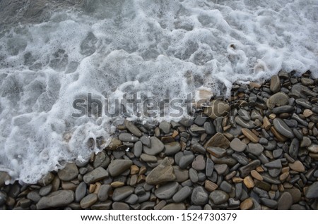 Sea wave on pebble beach photo background. Pebble beach stones with sea wave. Stones of Adriatic coastline. Seaside banner template with place for text. Seashore foamy wave. 