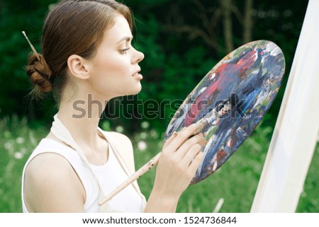 a woman an easel to oil paints paints a picture