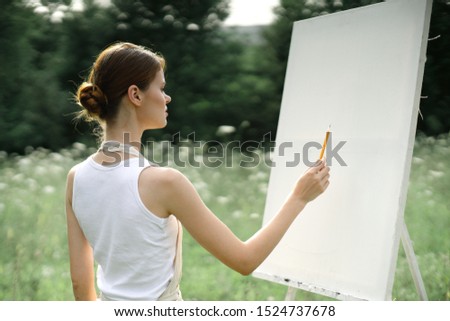 woman easel with white canvas paints a picture