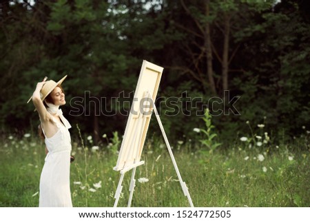 beautiful woman in nature paints a picture an easel