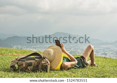 Asian woman lie on grassland and take a picture