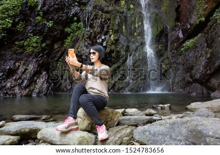 Asian woman selfie near the waterfall at outdoor