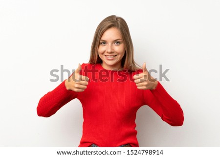 Young blonde woman with red sweater over isolated white background giving a thumbs up gesture