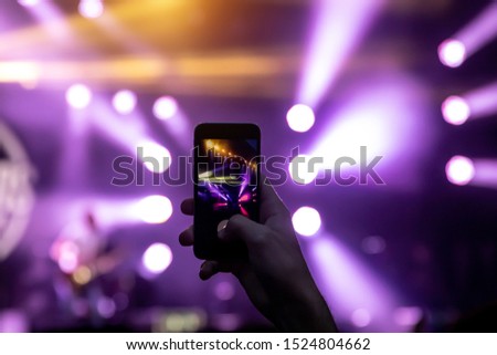 Hands with a smartphone records live music festival, live concert