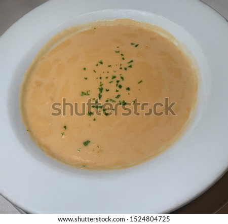 A bowl of delicious lobster bisque soup  with a sprinkling of fresh parsley.
