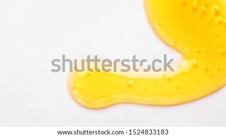 Yellow serum or olive oil drop texture isolated on white background, transparent bubble gel cosmetic sample. Golden liquid acid cream swatch or honey drip. Close up skin cosmetic lotion macro top view Royalty-Free Stock Photo #1524833183