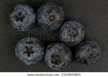 Group of six whole fresh blue blueberry flatlay on grey stone