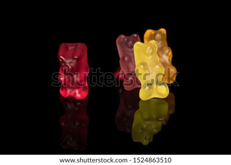 Group of four whole gummy bear isolated on black glass