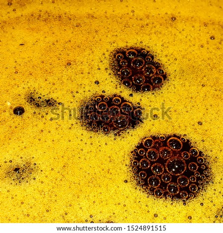 Yellow and brown bubbling surface of a liquid caramel boiling. Background texture of cooking theme. Bright bubbles.