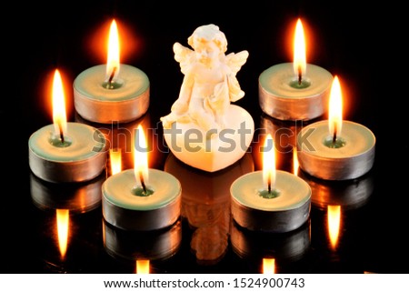 Angel messenger, with wings and bright candles around. In religions, it is a spiritual, incorporeal being who communicates the will of God and has supernatural powers. The candle is a symbol of life. 