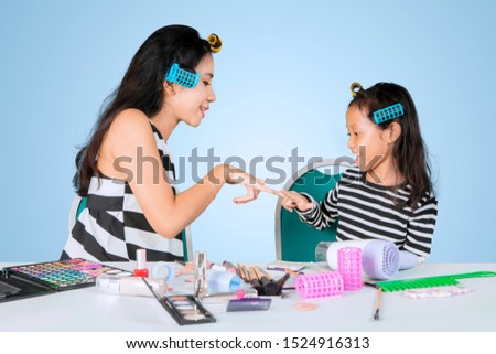 Picture of a little girl having fun with her mother after doing makeup in the studio