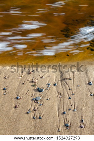 Bubbles from rapids in the waters of the Hurrican River swirl against a sand bar at the mouth of the river at the Lake Superior Shore, Pictured Rocks National Lakeshore, Alger County, Michigan