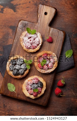 Set of sweet cakes with berries on wooden board. Strawberry, raspberry and blackberry
