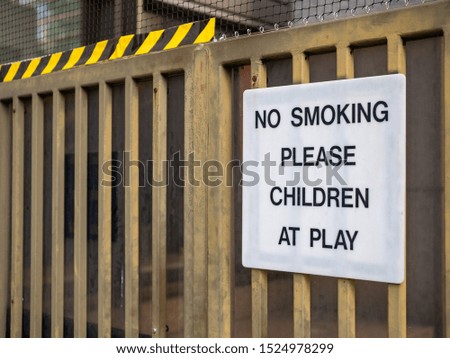 No smoking please, children at play sign on fence at a recreational playground area