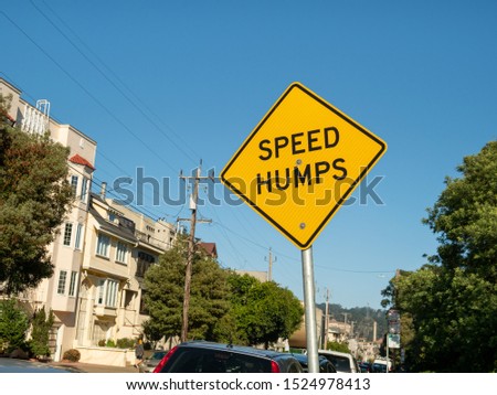 Yellow speed humps caution sign hinging in residential area on a sunny day