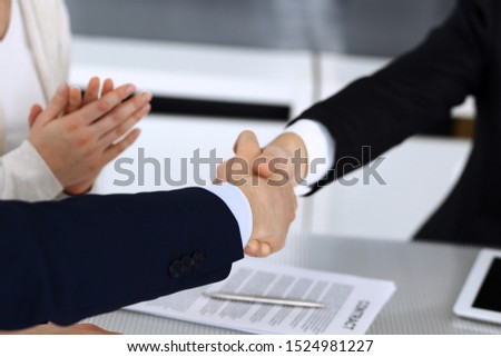 Business people shaking hands after contract signing at the glass desk in modern office. Unknown businessman, male entrepreneur with colleagues at meeting or negotiation. Teamwork, partnership and