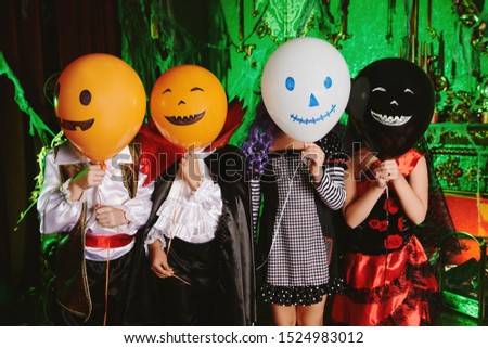Funny children in carnival costumes with balloons on Halloween. Halloween party.
