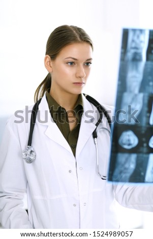 Doctor woman examining x-ray picture in hospital. Surgeon or orthopedist at work in clinic. Medicine and healthcare concept