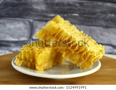 Honeycombs with honey and pollen on a white plate.