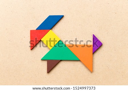 Color tangram puzzle in goat shape on wood background