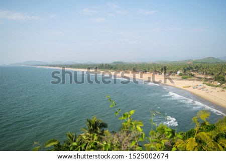 Beautiful coastline of gokarna beach, coast and sea view from high, India with people walking around and swimming in the water, green hills, seashore