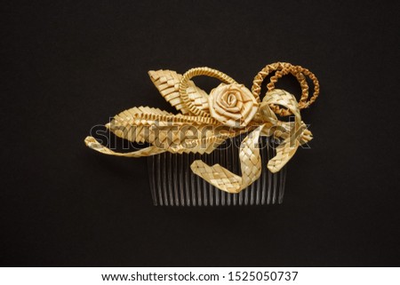 Ornamental hair comb with straw flowers on a dark background