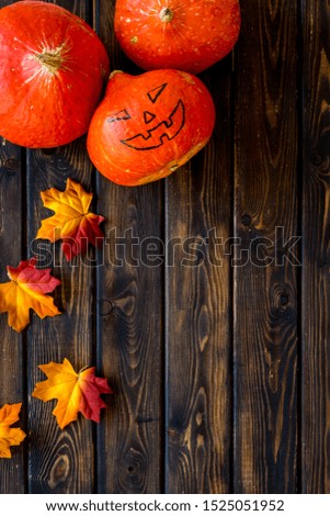 Scary Halloween pumpkin with drawn face on dark wooden background top view copy space
