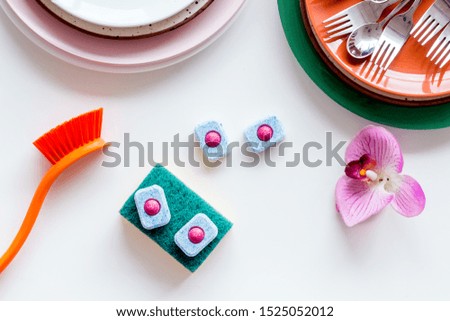 Dry detergent for dishwashing near plates and orchid flower on white background top view