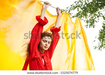 young woman in a red dress with a yellow cloth on nature