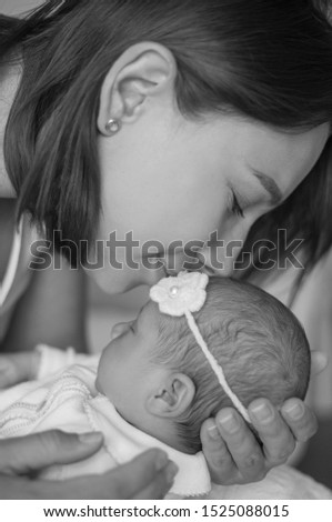 Close-up. Mom gently kisses the baby. Cute newborn baby sleeping in mother's arms.