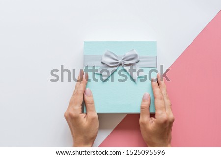 Abstract background with Hands holding gift box in modern style. Xmas background. Holiday mockup. Christmas greeting card. Package icon. Happy birthday. Flat lay, top view style. Shopping sale concept